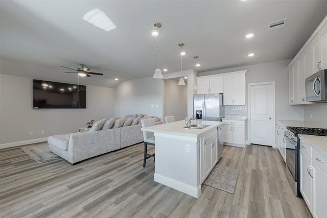 a large white kitchen with a stove a sink and a refrigerator