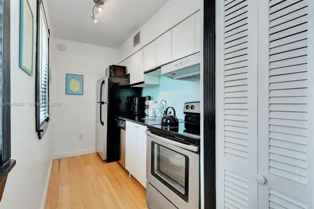 a kitchen with stainless steel appliances granite countertop white cabinets and refrigerator