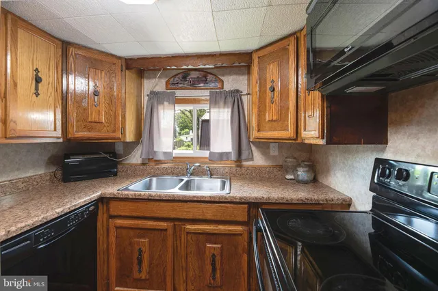 a kitchen with granite countertop stainless steel appliances a sink window and cabinets