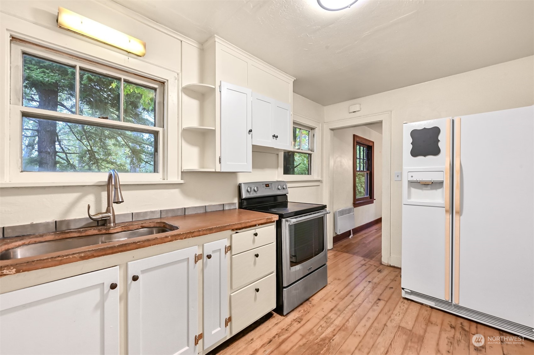4144 Rural Avenue Bellingham, WA 98226 - Photo 18 of 26 a kitchen with stainless steel appliances granite countertop a stove a sink and white cabinets with wooden floor next to windows