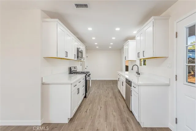a kitchen with white cabinets appliances and sink