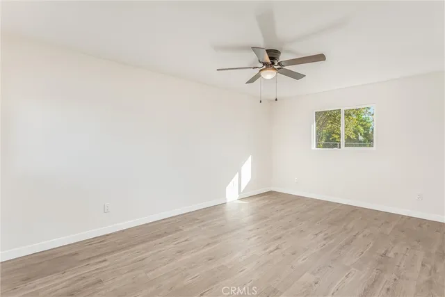 an empty room with wooden floor fan and windows