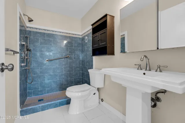 a bathroom with a sink a toilet a mirror and shower