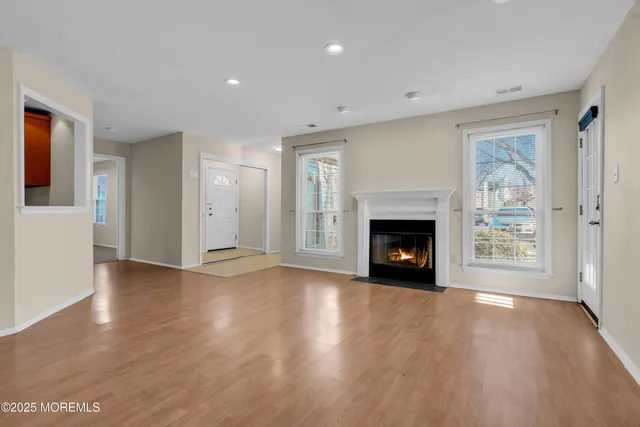 a view of an empty room with wooden floor fireplace and a window