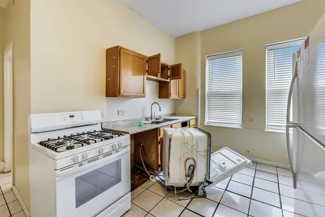 a kitchen with stainless steel appliances granite countertop a stove top oven a sink a dining table and chairs with wooden floor