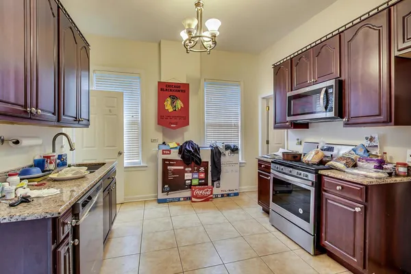 a kitchen with stainless steel appliances granite countertop a stove top oven a sink a dining table and chairs with wooden floor