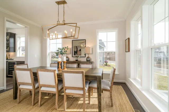 a dining room with wooden floor a chandelier a wooden table and chairs