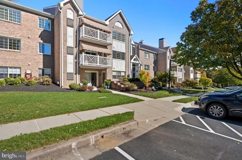 a front view of a building with a garden and trees