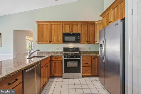 a kitchen with stainless steel appliances granite countertop a stove top oven microwave and view of living room