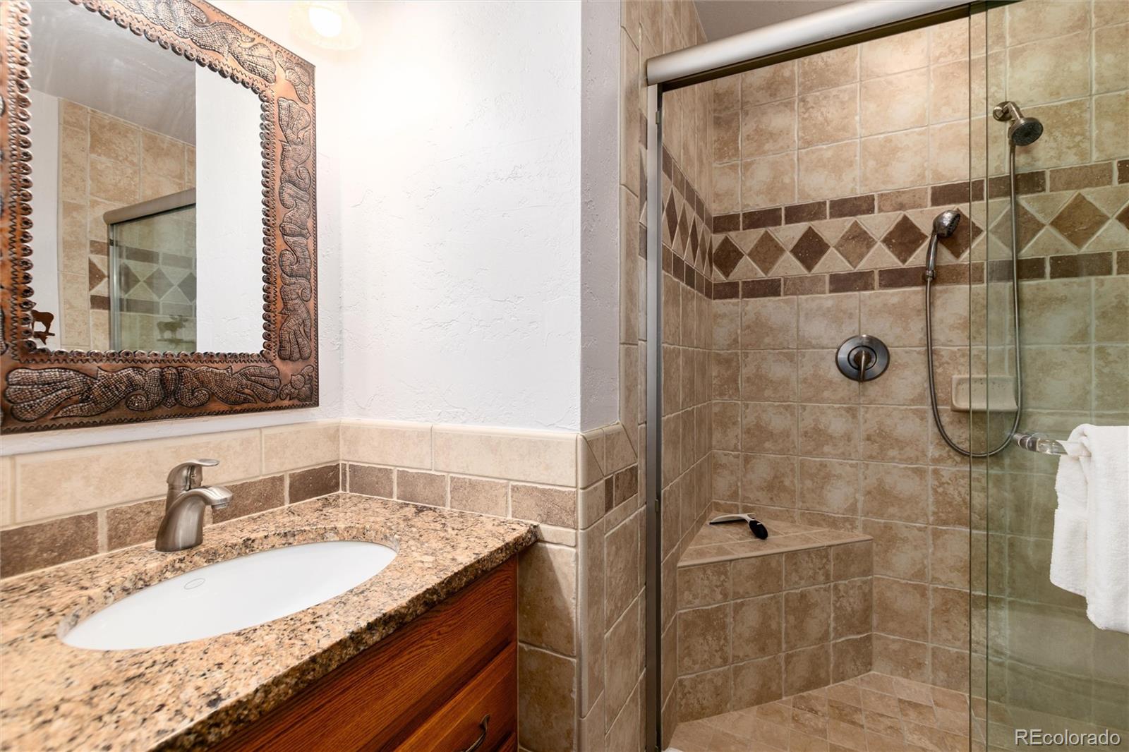 490 Kings Crossing Road, Unit 631633 Winter Park, CO 80482 - Photo 28 of 43 a bathroom with a granite countertop shower a sink and a mirror