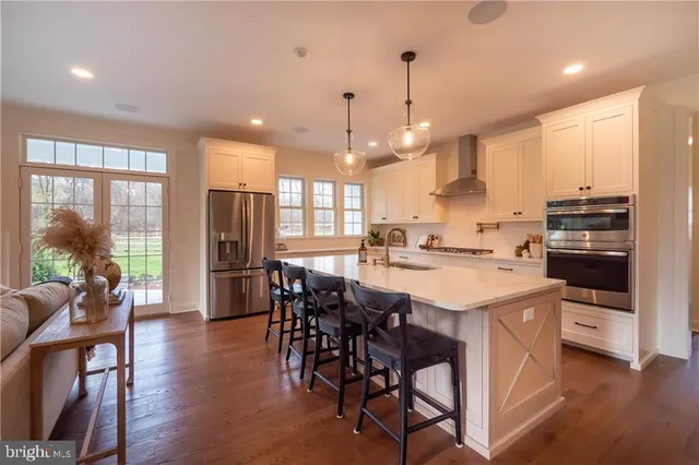 a kitchen with stainless steel appliances kitchen island granite countertop a stove a refrigerator a kitchen island with a dining table and chairs