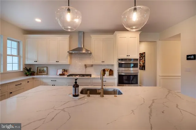 a kitchen with stainless steel appliances kitchen island granite countertop a stove and white cabinets