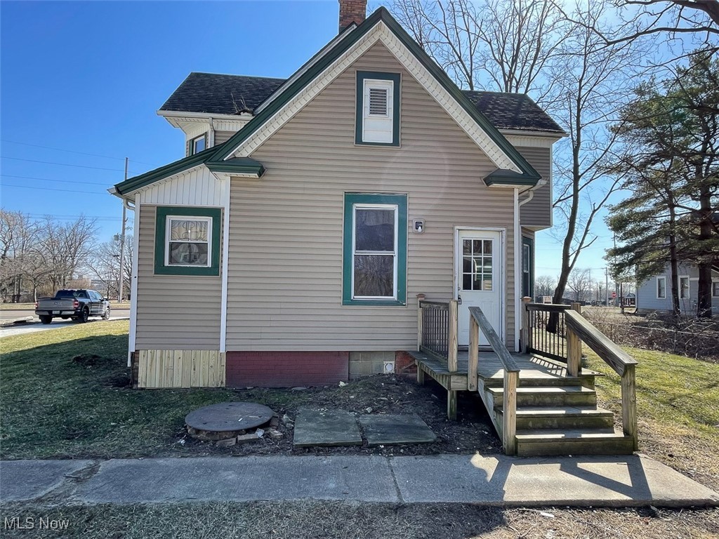 View of back of property featuring a chimney and roof with shingles