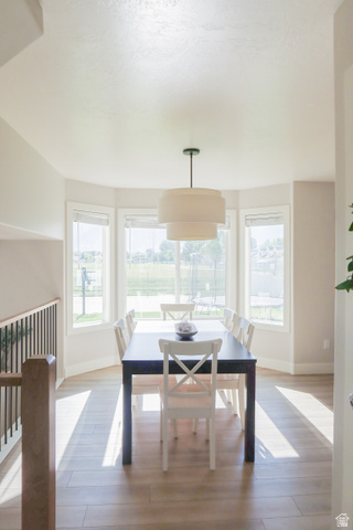 1204 North 3020th Street West Provo, UT 84601 - Photo 17 of 35 Bay window dining area featuring wood-finish flooring, a tiered pendant light fixture, and black metal railing with a wood cap