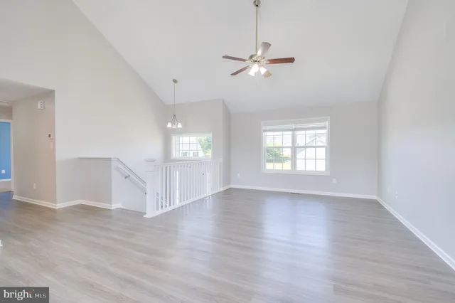 an empty room with wooden floor chandelier and windows