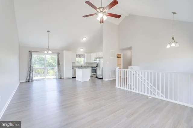 a view of a room with wooden floor white walls and windows