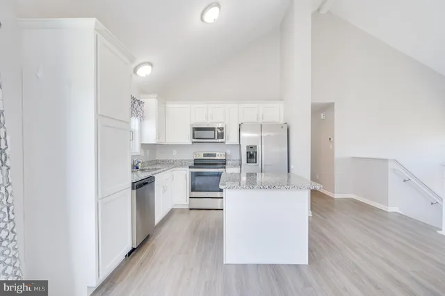 a kitchen with stainless steel appliances a refrigerator a stove top oven and wooden floors