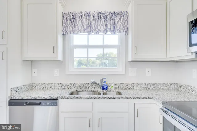 a kitchen with granite countertop white cabinets and a window