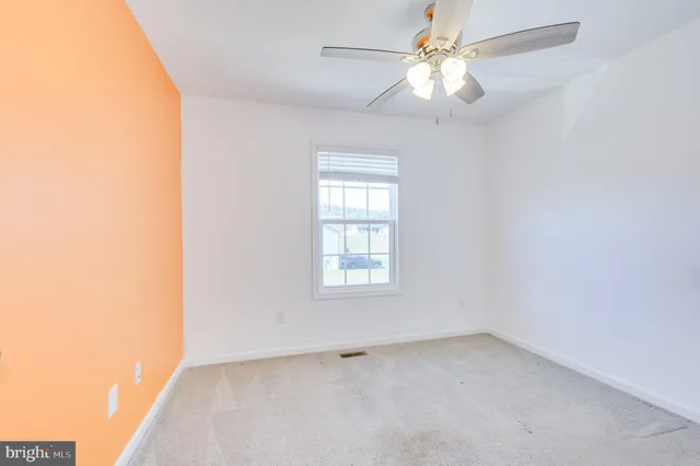 an empty room with a window and a fan