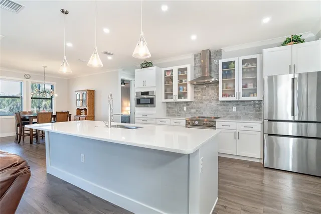 a kitchen with stainless steel appliances granite countertop a refrigerator a sink dishwasher a oven with white cabinets and wooden floor