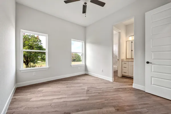 an empty room with wooden floor cabinet and windows