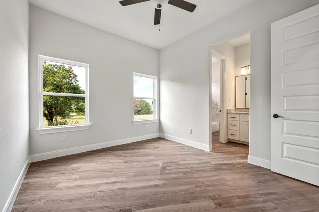 an empty room with wooden floor cabinet and windows