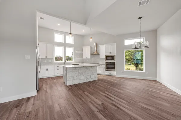 a large kitchen with kitchen island white cabinets and stainless steel appliances