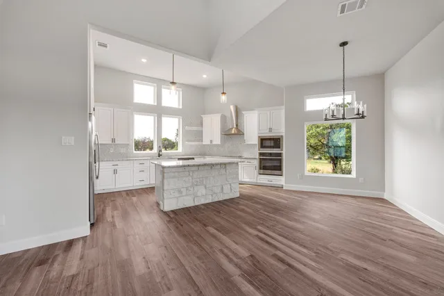 a large kitchen with kitchen island white cabinets and stainless steel appliances