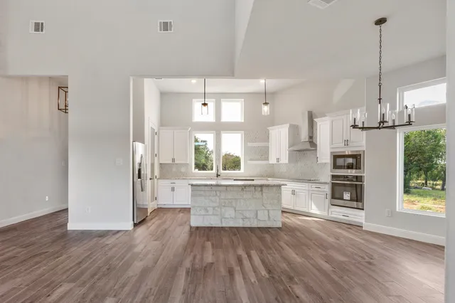 a large kitchen with cabinets wooden floor and stainless steel appliances