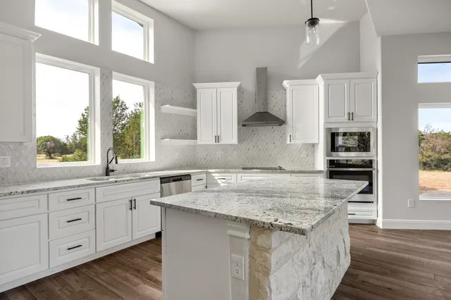 a kitchen with granite countertop a sink a counter space appliances and cabinets