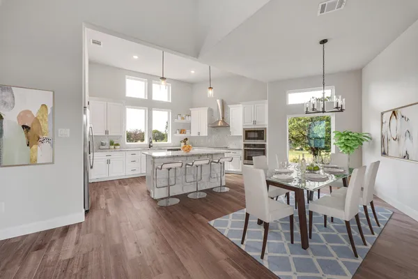 a kitchen with stainless steel appliances kitchen island granite countertop a stove a sink dishwasher a dining table and chairs with wooden floor