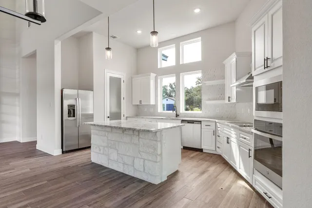 a large kitchen with stainless steel appliances granite countertop a lot of counter space and wooden floors