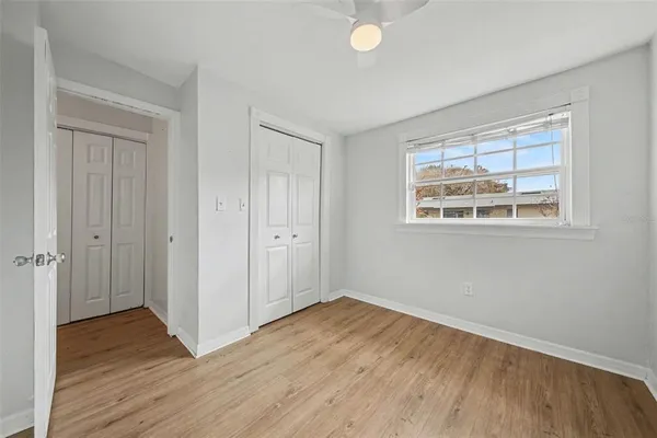 a view of empty room with wooden floor and fan