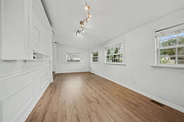 a view of an empty room with wooden floor and a window