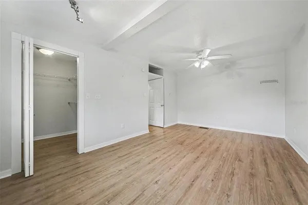 an empty room with wooden floor and fan