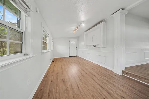 a view of empty room with wooden floor and fan