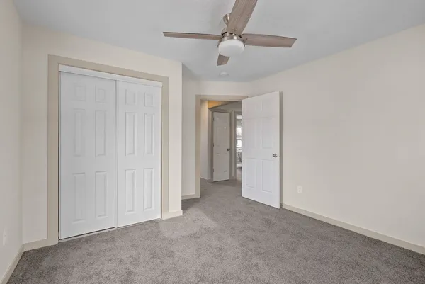 an empty room with a ceiling fan and closet area