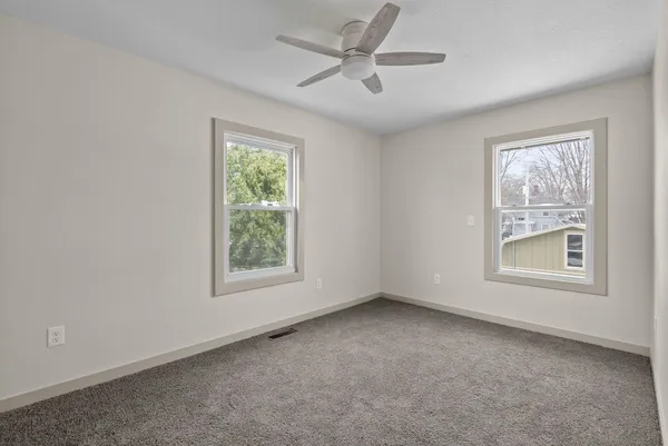 an empty room with a window and a fan