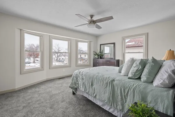 a bedroom with a large bed and two windows
