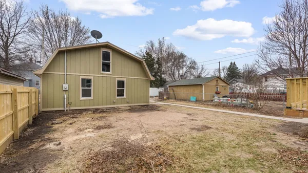 a view of a grey house with wooden fence