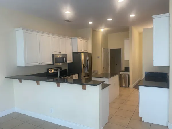 a kitchen with stainless steel appliances granite countertop a refrigerator a sink a stove with white cabinets