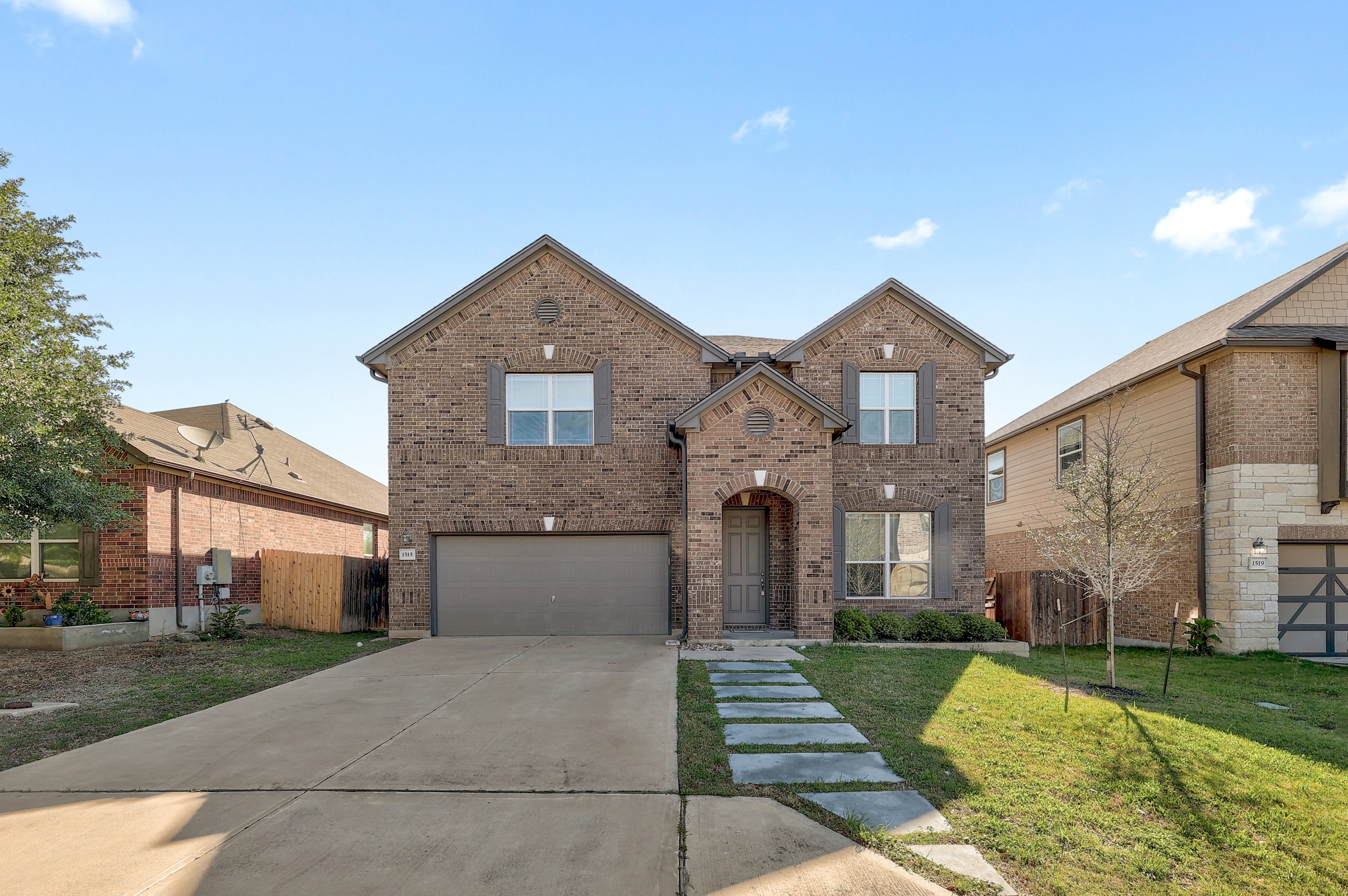 View of front of property featuring brick siding, concrete driveway, and a garage