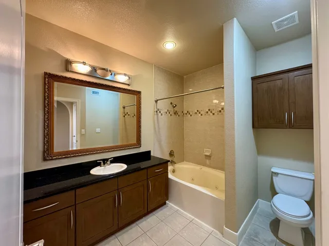 a bathroom with a granite countertop sink toilet mirror and bathtub