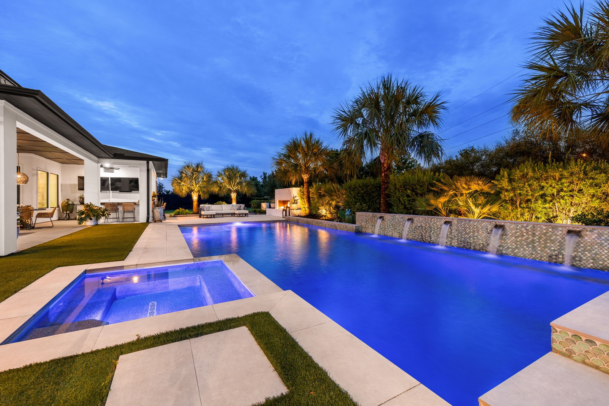 27903 Indigo Ridge Drive Fulshear, TX 77441 - Photo 48 of 50 Resort-style pool and spa with illuminated water features, tropical landscaping, and an expansive outdoor living area.
