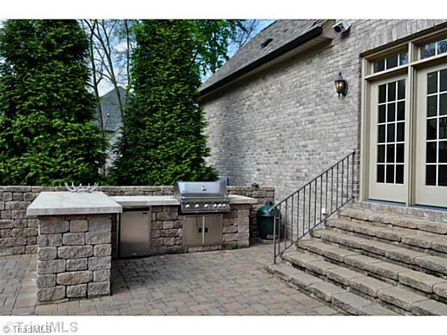 7045 Denison Road Summerfield, NC 27358 - Photo 14 of 16 Patio/Deck. Outside a large cobbled terrace is home to an outdoor kitchen with a stainless steel Jenn- Air grille and under counter refrigerator.