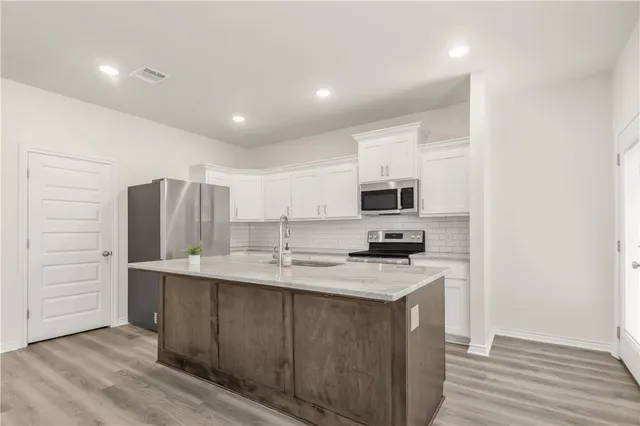 a kitchen with stainless steel appliances granite countertop a sink a stove and refrigerator