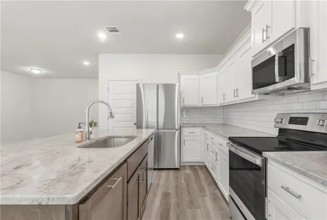 a kitchen with stainless steel appliances granite countertop a sink and stove top oven