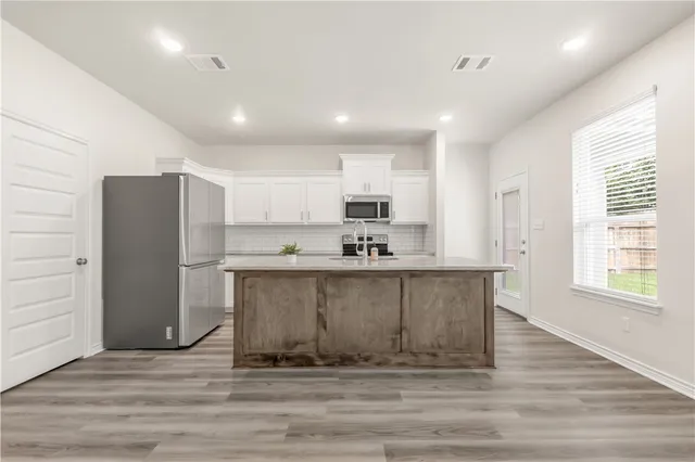 a living room with stainless steel appliances kitchen island granite countertop a refrigerator stove and wooden cabinets