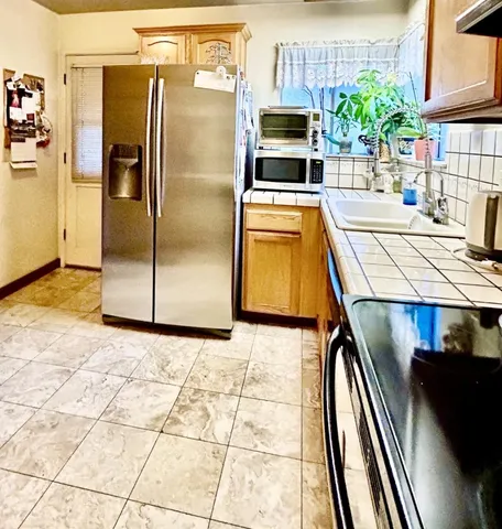 a kitchen with stainless steel appliances kitchen island granite countertop a refrigerator a stove and a sink