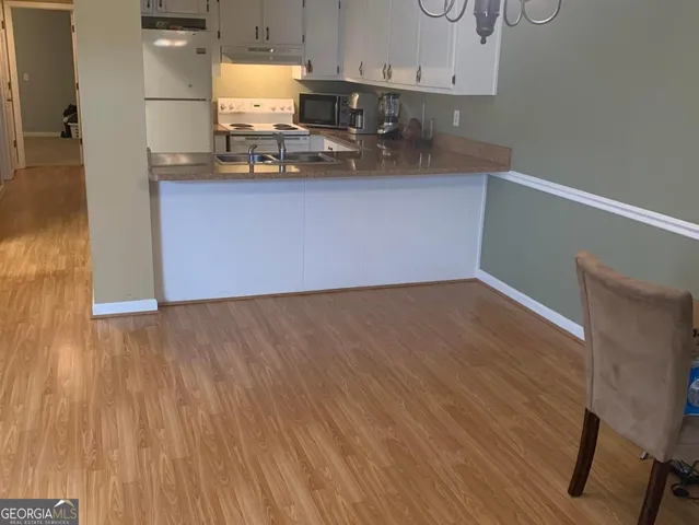 a kitchen with granite countertop white cabinets and wooden floor